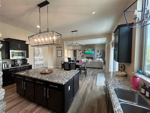 kitchen with pendant lighting, sink, dark hardwood / wood-style floors, stainless steel microwave, and a kitchen island