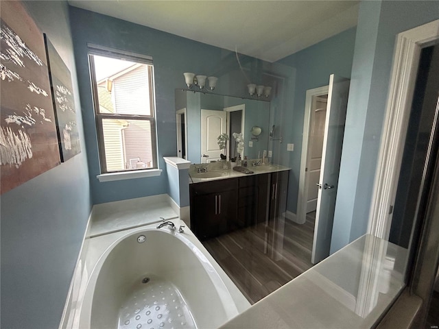 bathroom with a washtub, vanity, and wood-type flooring