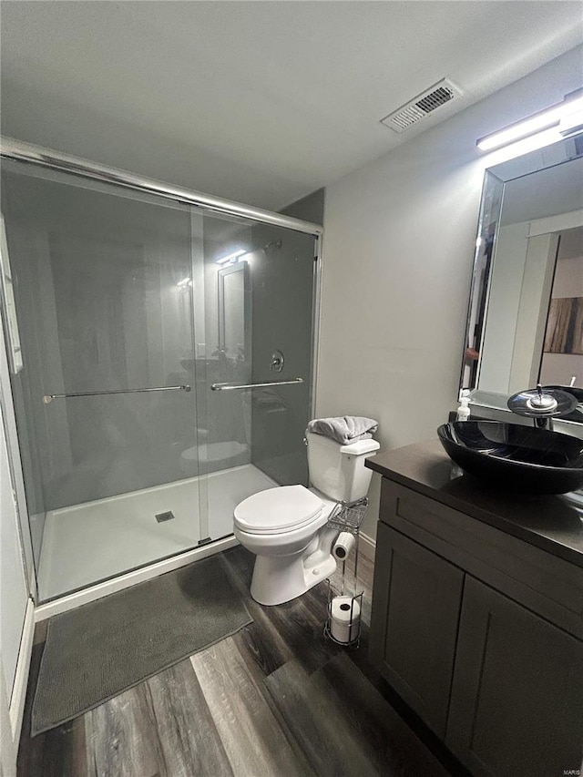 bathroom with hardwood / wood-style flooring, vanity, toilet, and walk in shower