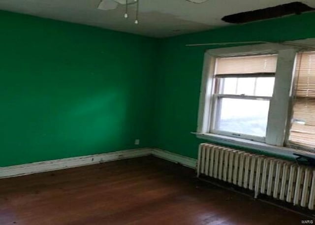 empty room featuring ceiling fan, radiator heating unit, and wood-type flooring