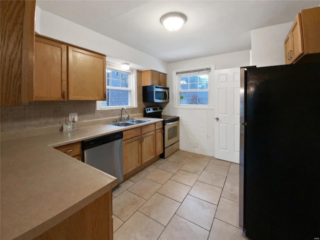 kitchen featuring tile walls, sink, light tile patterned floors, and appliances with stainless steel finishes