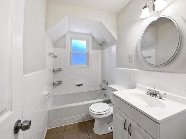 full bathroom with tile walls, tile patterned flooring, vanity, tiled shower / bath, and toilet