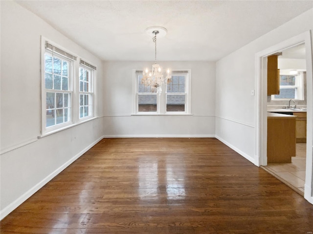 unfurnished dining area featuring sink, a chandelier, and dark hardwood / wood-style flooring