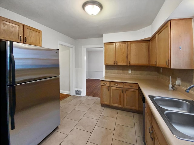 kitchen with sink, built in desk, light tile patterned floors, appliances with stainless steel finishes, and backsplash