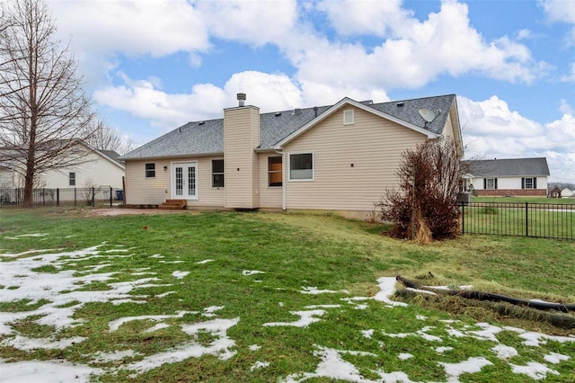 back of property with entry steps, a fenced backyard, a yard, french doors, and a chimney