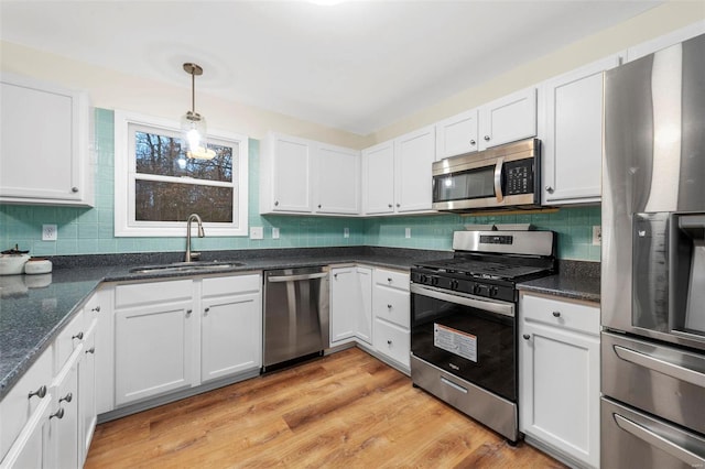 kitchen featuring decorative backsplash, white cabinets, appliances with stainless steel finishes, light wood-type flooring, and a sink