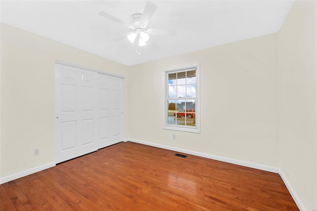 unfurnished bedroom with a ceiling fan, visible vents, baseboards, a closet, and wood-type flooring