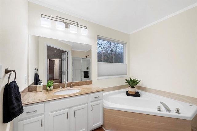 bathroom featuring a stall shower, ornamental molding, a garden tub, and vanity