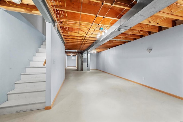 unfinished basement featuring heating unit, baseboards, and stairway