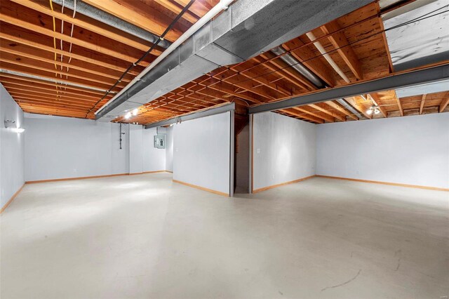 unfinished basement featuring electric panel and baseboards