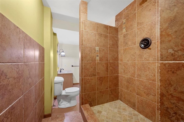 bathroom with tiled shower, toilet, and tile patterned floors