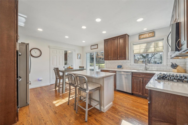 kitchen featuring a breakfast bar area, light hardwood / wood-style floors, a center island, and appliances with stainless steel finishes