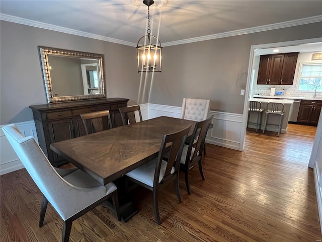 dining room featuring ornamental molding, sink, a notable chandelier, and dark hardwood / wood-style flooring