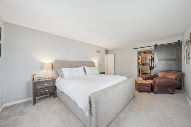 carpeted bedroom featuring a walk in closet, a barn door, and a closet