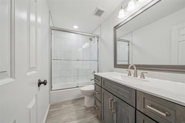 full bathroom featuring vanity, toilet, and combined bath / shower with glass door