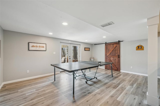 playroom featuring a barn door, light hardwood / wood-style flooring, and french doors