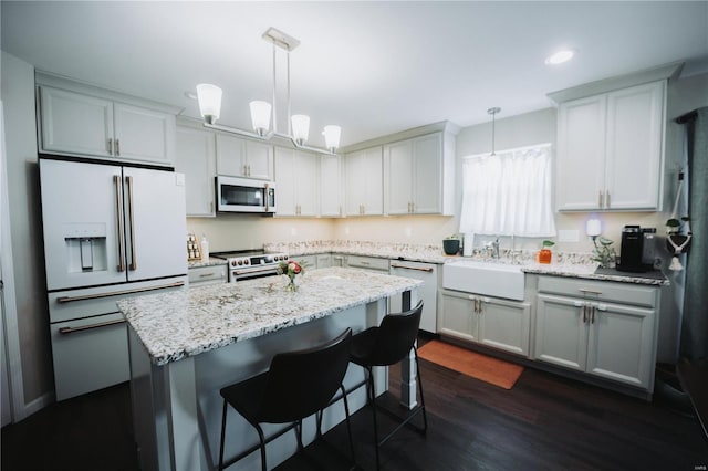 kitchen featuring a kitchen island, sink, pendant lighting, and white appliances