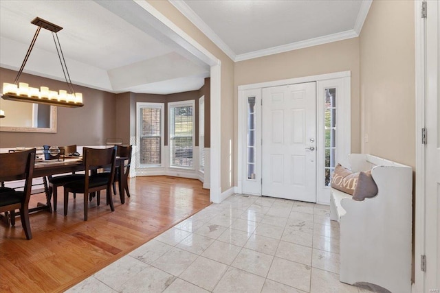 entryway featuring ornamental molding, a notable chandelier, light wood-style floors, and baseboards