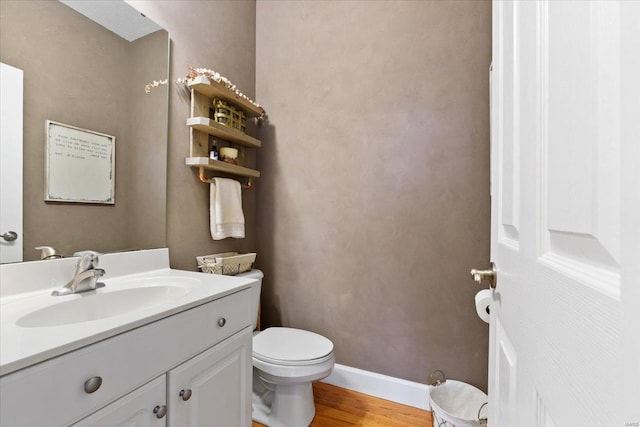 bathroom with wood finished floors, vanity, toilet, and baseboards