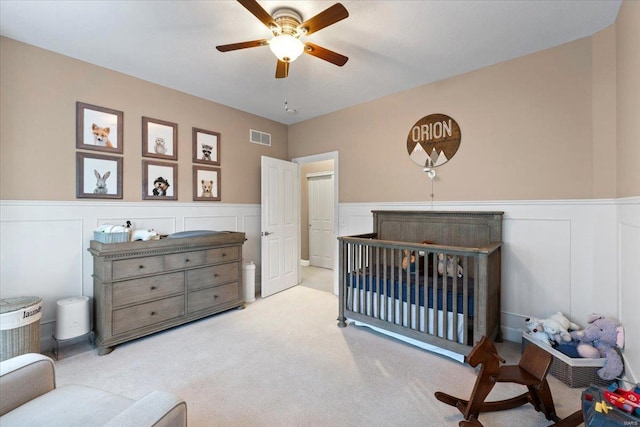 bedroom featuring a wainscoted wall, carpet, visible vents, and ceiling fan