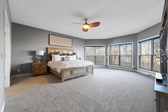 bedroom featuring a ceiling fan, carpet flooring, baseboards, and multiple windows