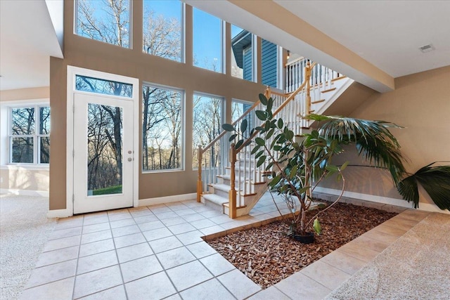 doorway to outside with a towering ceiling, baseboards, stairway, and tile patterned flooring