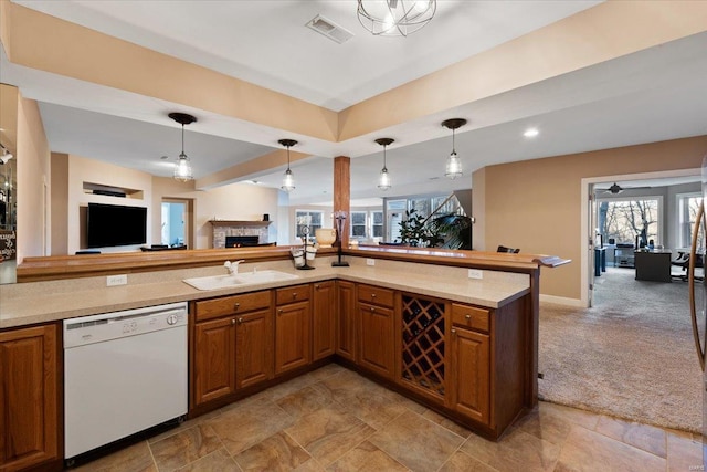 kitchen featuring brown cabinets, visible vents, open floor plan, white dishwasher, and a sink