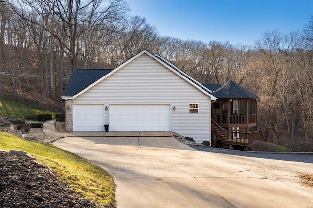 view of property exterior with driveway, an attached garage, and a sunroom