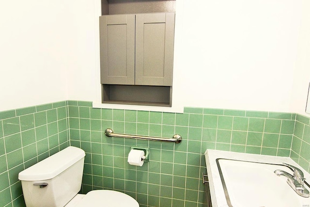 bathroom featuring toilet, sink, and tile walls