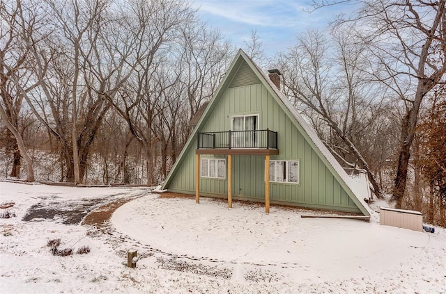 exterior space with a balcony, a chimney, and board and batten siding