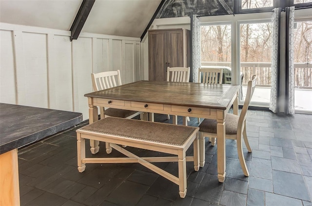 dining space featuring vaulted ceiling with beams and stone tile flooring