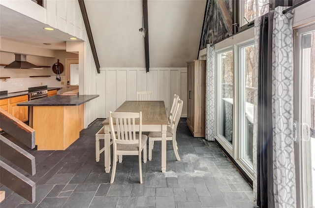 dining space with stone finish floor and vaulted ceiling