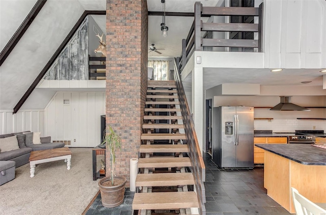 stairs with a high ceiling, visible vents, and a ceiling fan