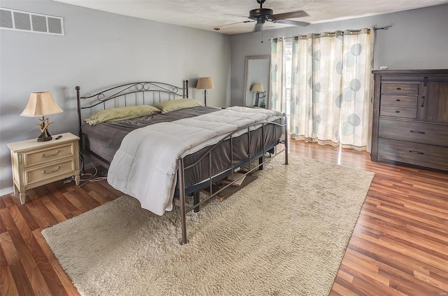 bedroom featuring ceiling fan, visible vents, and dark wood finished floors