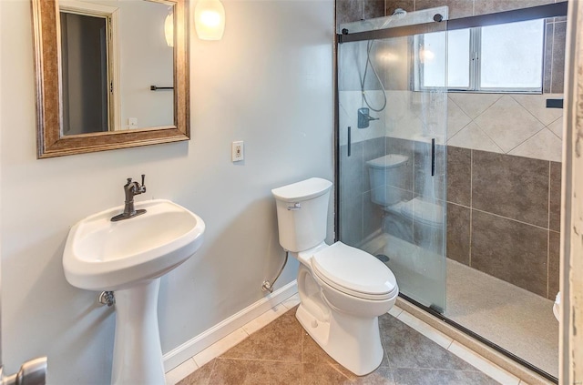 bathroom featuring baseboards, a stall shower, toilet, and tile patterned floors