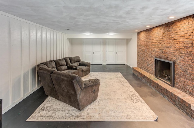 living area featuring a textured ceiling, a brick fireplace, and finished concrete floors