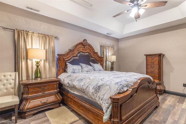 bedroom featuring hardwood / wood-style flooring, ceiling fan, and a tray ceiling