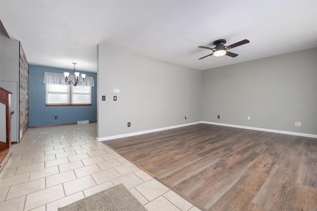 spare room with ceiling fan with notable chandelier and light hardwood / wood-style flooring