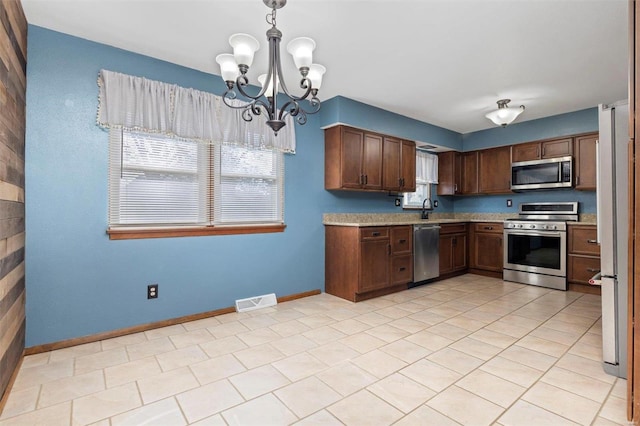 kitchen featuring light tile patterned flooring, sink, an inviting chandelier, hanging light fixtures, and appliances with stainless steel finishes