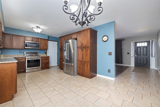 kitchen featuring sink, an inviting chandelier, stainless steel appliances, light tile patterned flooring, and decorative light fixtures