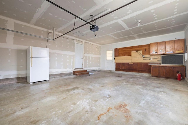 garage with a garage door opener and white fridge