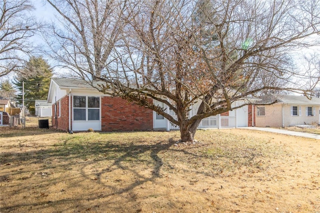 exterior space featuring a yard, cooling unit, brick siding, and fence