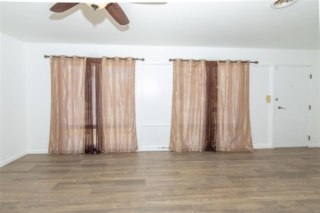 unfurnished room with ceiling fan, wood finished floors, and visible vents