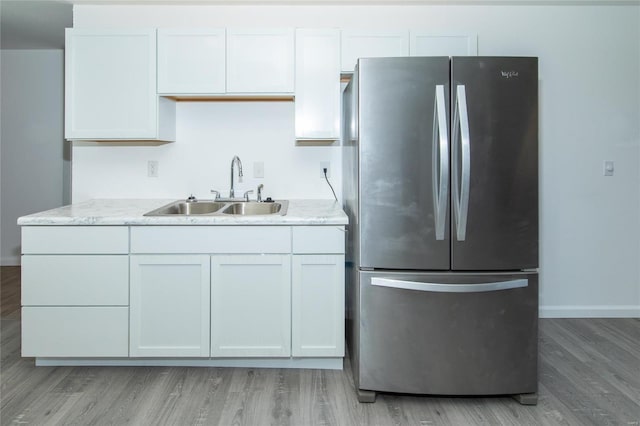 kitchen featuring a sink, white cabinetry, baseboards, light wood-style floors, and freestanding refrigerator