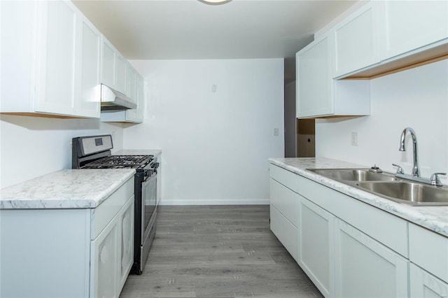 kitchen with white cabinetry, sink, stainless steel gas range, and light hardwood / wood-style flooring