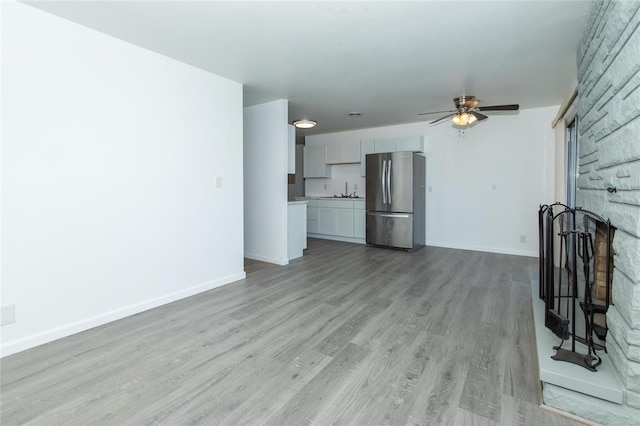 unfurnished living room featuring ceiling fan and light wood-type flooring