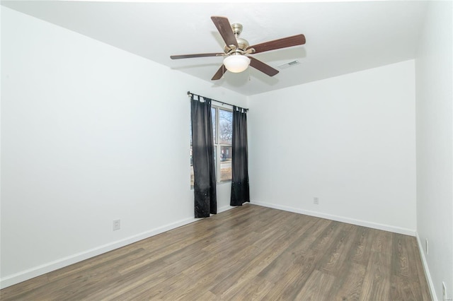 spare room with ceiling fan, wood finished floors, visible vents, and baseboards