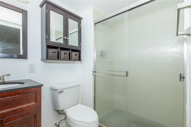 bathroom with vanity, a shower stall, and toilet