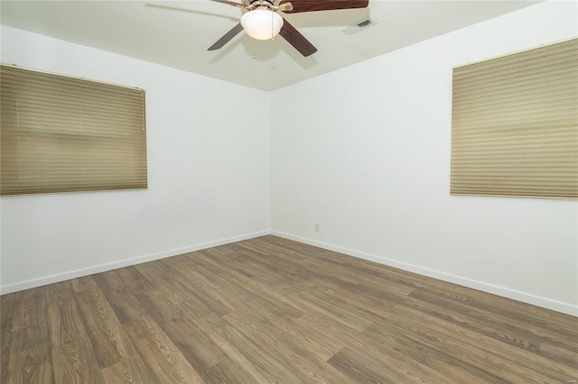 unfurnished room featuring baseboards, visible vents, and wood finished floors