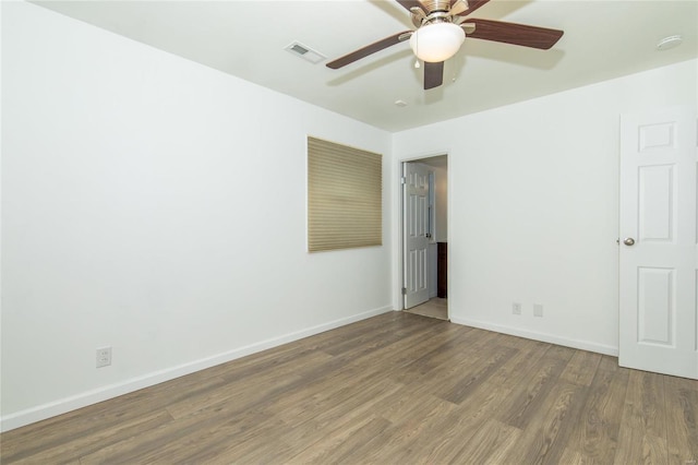 empty room with baseboards, visible vents, ceiling fan, and wood finished floors